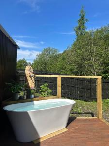 a bath tub sitting on a deck next to a fence at Appin Holiday Homes -Caravans, Lodges, Shepherds Hut and Train Carriage stays in Appin