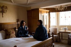 Un uomo e una donna seduti su un letto di The Old Inn a Crawfordsburn