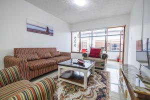 a living room with two couches and a table at Safi Smart Self-catering Suite 1 in East London
