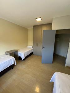 una habitación de hotel con 2 camas y una puerta en Astor Hostel, en Campinas