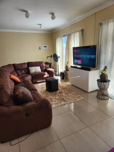 Dollar Zone في منزيني: غرفة معيشة مع أريكة بنية وتلفزيون بشاشة مسطحة