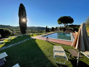 un cortile con piscina e ombrellone di Fattoria Di Pancole a San Gimignano