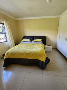 ein Schlafzimmer mit einem Bett mit gelber Decke in der Unterkunft Dollar Zone in Manzini