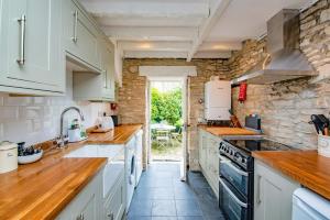 a kitchen with white cabinets and a stone wall at Cosy Little Hyde Cottage, Swanage in Swanage