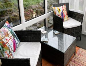eine Veranda mit zwei Stühlen und einem Glastisch in der Unterkunft Horseshoe Cottage Aberaeron in Ciliau-Aeron