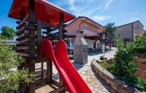 un parque infantil con un tobogán rojo en un patio en Lovely Apartment In Kavran With Wifi, en Kavran