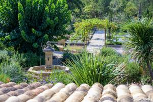 einen Garten mit einem Bogen, einem Brunnen und Pflanzen in der Unterkunft DOMAINE jusqu'à 16 personnes - 3 Villas - 3 Piscines in Villecroze