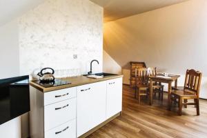 Apartamenty i Domki Orawskie في Zubrzyca Dolna: مطبخ مع دواليب بيضاء وطاولة مع كراسي