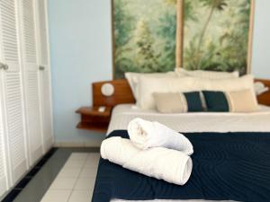 two towels sitting on a bed in a bedroom at Bungalow La Kawannaise - Piscine, Terrasse, Plage in Grand-Bourg
