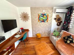 a living room with a tv and a couch and a desk at Bungalow Agathe - Piscine, Wifi, Farnienté et Plage à 2 minutes in Grand-Bourg
