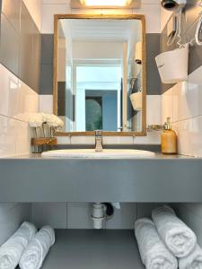 a bathroom with a sink and a mirror and towels at Bungalow La Kawannaise - Piscine, Terrasse, Plage in Grand-Bourg
