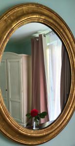 un miroir avec un vase et une rose rouge. dans l'établissement La Casa della Rosa Nana, à Trezzano sul Naviglio
