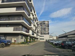um prédio alto com carros estacionados em um estacionamento em Nana Apartaments em Cluj-Napoca