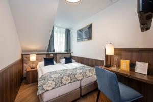 ein Hotelzimmer mit einem Bett, einem Schreibtisch und einem Stuhl in der Unterkunft Salzburg Hotel Lilienhof in Salzburg