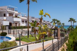 a resort with a swimming pool and palm trees at Pura Vida Beach Apartment by Perfectly Rentals in Torrevieja