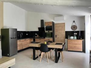 a kitchen with a wooden table and a refrigerator at Villa charmante à Châteaurenard avec piscine privée in Châteaurenard