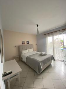 een witte slaapkamer met een bed en een tafel bij Villa Rozou in Paralia Vrachou