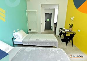 a room with two beds and a desk with a table at The City Flats Sacred Heart in Manila