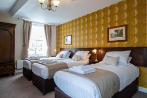 duas camas num quarto de hotel com papel de parede amarelo em White Lion Royal Hotel em Bala
