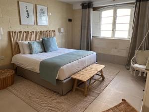 a bedroom with a bed and a bench and a window at Ogygia Suites Gozo in Għarb