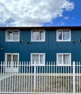 uma casa azul com uma cerca branca em frente em Bahía Golondrina 2 em Ushuaia