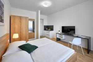 a white bedroom with a bed and a television at DownTown Suites Belohorska in Prague