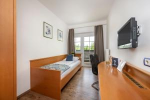 ein Hotelzimmer mit einem Bett, einem Schreibtisch und einem TV in der Unterkunft Salzburg Hotel Lilienhof in Salzburg