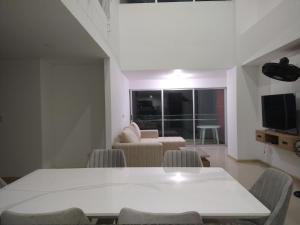 - un salon avec une table et des chaises blanches dans l'établissement Lujoso Penthouse, à Buenaventura