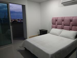 - une chambre avec un grand lit et une tête de lit rose dans l'établissement Lujoso Penthouse, à Buenaventura