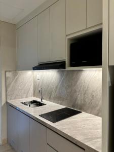 a kitchen with white cabinets and a counter top at Apartment Podomoro Medan in Medan