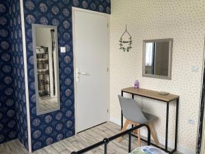 Zimmer mit einem Tisch, einem Stuhl und einem Spiegel in der Unterkunft La Maison Bleue in Préveranges