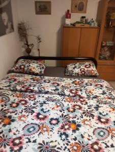 a bed with a floral comforter and two pillows on it at Le Palme in Monte Ceneri