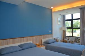金城鎮的住宿－金門沐風民宿 ，一间卧室设有两张床和蓝色的墙壁