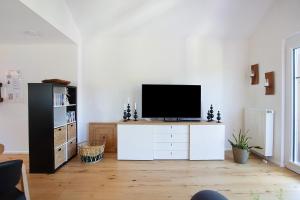 a living room with a television on a white cabinet at Quellenhof Südschwarzwald in Murg