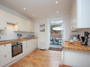 a kitchen with white cabinets and a wooden floor at 2 Central, spacious, apartment with private patio in Sidmouth
