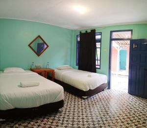 2 camas en una habitación con paredes azules en Manulalu B&B, en Bajawa