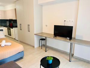 um quarto com uma secretária e uma televisão de ecrã plano em Elvita Apartments 4 em Atenas