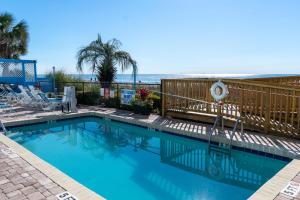 a swimming pool with the beach in the background at Beach Club at Montego Inn in Myrtle Beach