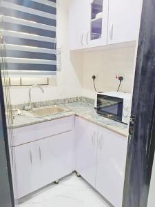 eine Küche mit weißen Schränken und einem Waschbecken in der Unterkunft blueocean.cog Apartments in Benin City