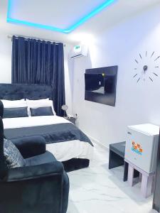 um quarto com uma cama, um sofá e uma televisão em blueocean.cog Apartments em Benin City