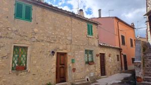an old stone building with colorful windows and doors at la casina della bubbolina in Semproniano