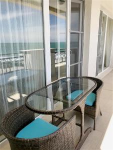 帕莫瑞的住宿－Private Super apartments by sea in Apart Hotel !，阳台上的玻璃桌和两把椅子