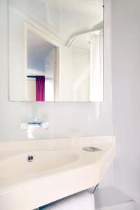 a white bathroom with a sink and a mirror at Premiere Classe Salon De Provence in Salon-de-Provence
