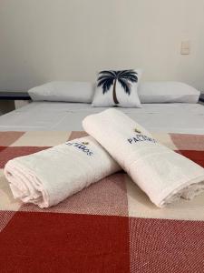 duas toalhas brancas estão deitadas numa cama em Pousada Palamós Uruaú em Beberibe
