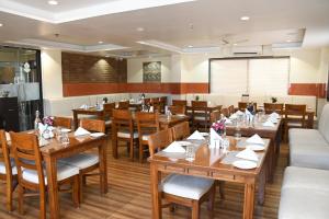 a restaurant with wooden tables and chairs and a screen at Sai Neem Tree Hotel in Shirdi