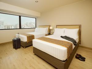 Habitación de hotel con 2 camas y ventana en Estelar Apartamentos Bellavista, en Lima