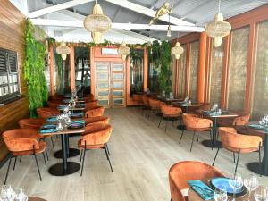 un ristorante con tavoli, sedie e piante di Bungalow La Kawannaise - Piscine, Terrasse, Plage a Grand-Bourg