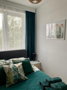 a bedroom with a bed with green sheets and a window at Chillout Airport Apartment KL33 - Free parking in Warsaw