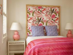 ハーバーアイランドにあるEleven Bahama Houseのベッドルーム1室(花柄のヘッドボードとランプ2つ付)