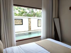 Un dormitorio con una cama y una ventana con piscina. en Hills House Villa by Globalstay - Jimbaran x Balangan x GWK, en Jimbaran